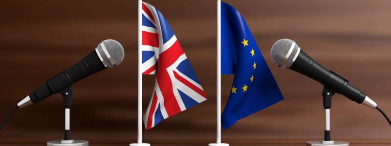 EU and UK miniature flags. Cable microphones, wooden background, banner. 3d illustration Relationship between European Union and England. Cable microphones on stands on a wooden background, banner. 3d illustration