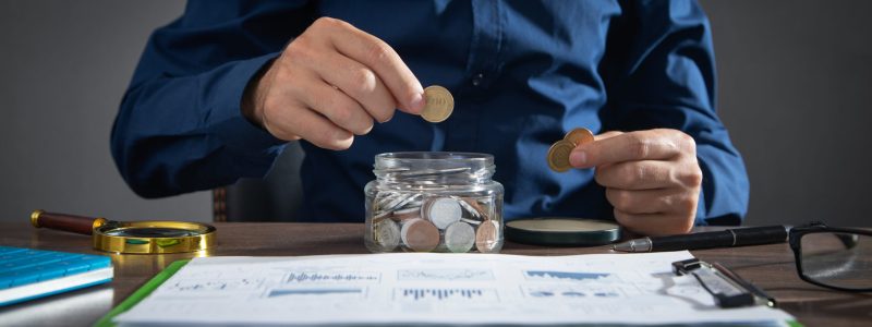 Businessman putting coin in glass bank. Saving money Businessman putting coin in glass bank. Saving money
