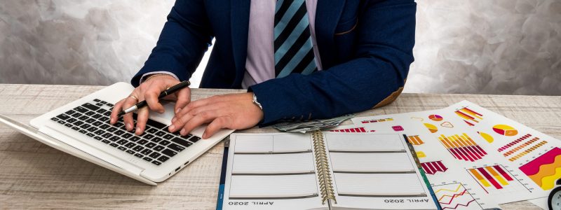 Businessman working in office with business graphs, laptop and notepad.